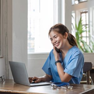 happy-female-doctor-using-laptop-to-do-data-work-and-chat-with-patients-on-the-phone-in-office-in-1-e1736279126261.jpg