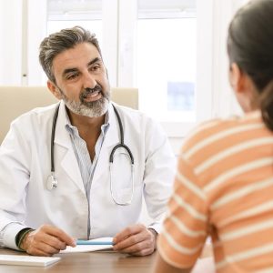 happy-male-doctor-talking-to-female-patient-in-clinic.jpg